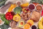 Variety of groceries, primarily fruits and vegetables, some whole, some cut.