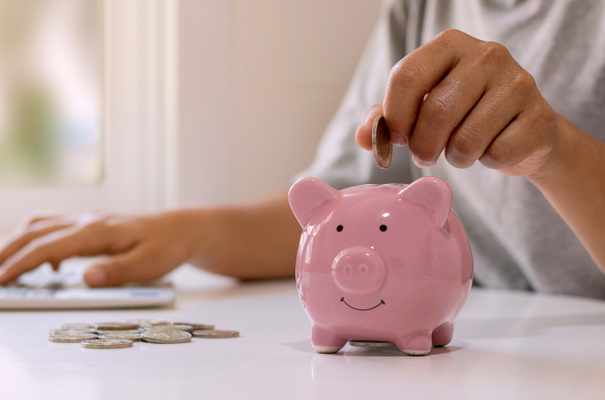 hand inserting coins into piggy bank
