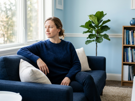 Femeie reflectând pe o canapea albastră într-un cabinet de psihoterapie luminos, simbolizând procesul de vindecare și reziliență după infidelitatea în cuplu la Clinica Blue.