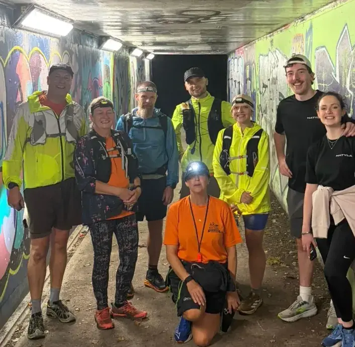 Rob Eberlein and his support runners wearing head torches in a graffiti-lined underpass beneath the A50