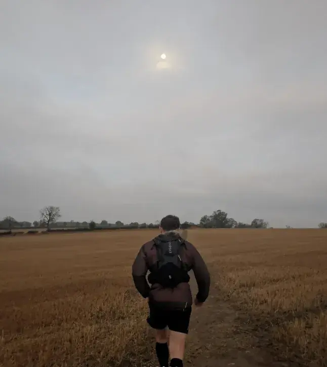 Rob Eberlein running along a field-edge path on the Leicestershire Round under a grey sky