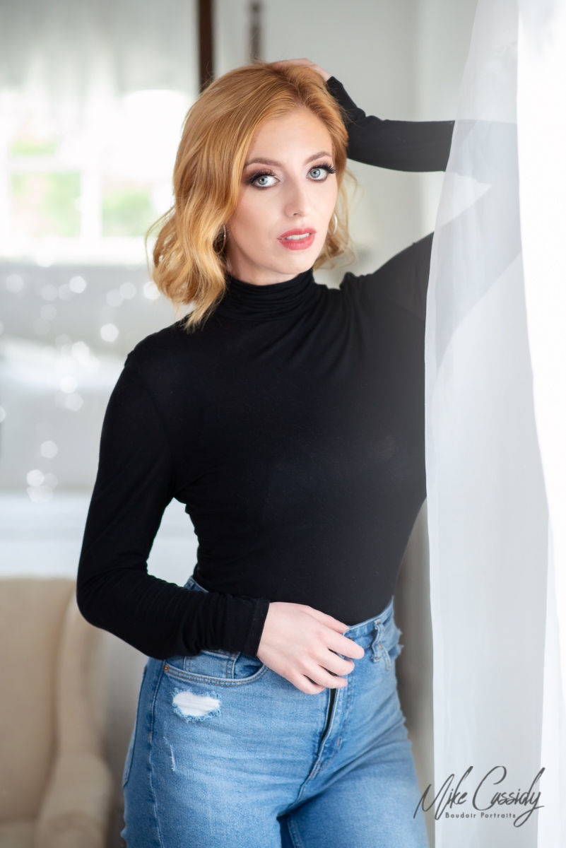 beautiful redheaded woman posing in jeans and black top