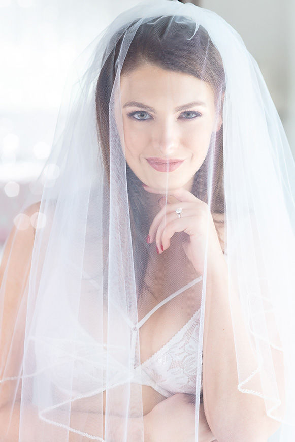 wedding boudoir photo of a beautiful brunette in white lingerie and a veil