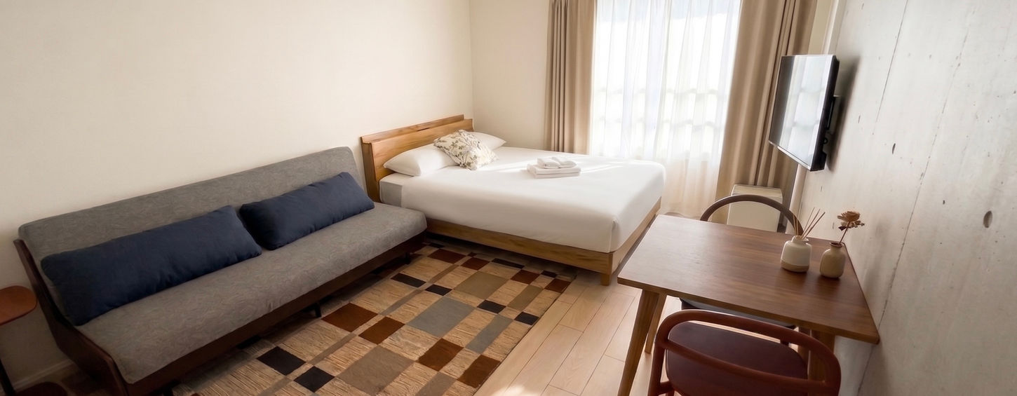 Modern living area with minimalist sofa and natural lighting in a furnished Tokyo otsuka serviced apartment for expats.