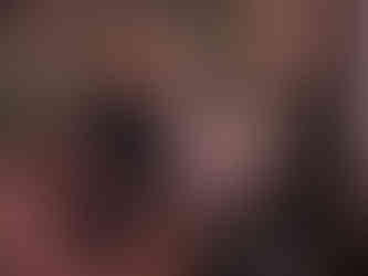 Woman in black dress on a patterned sofa, holding a green rotary phone. Dimly lit room with decorative lamps and framed pictures. She looks pensive.