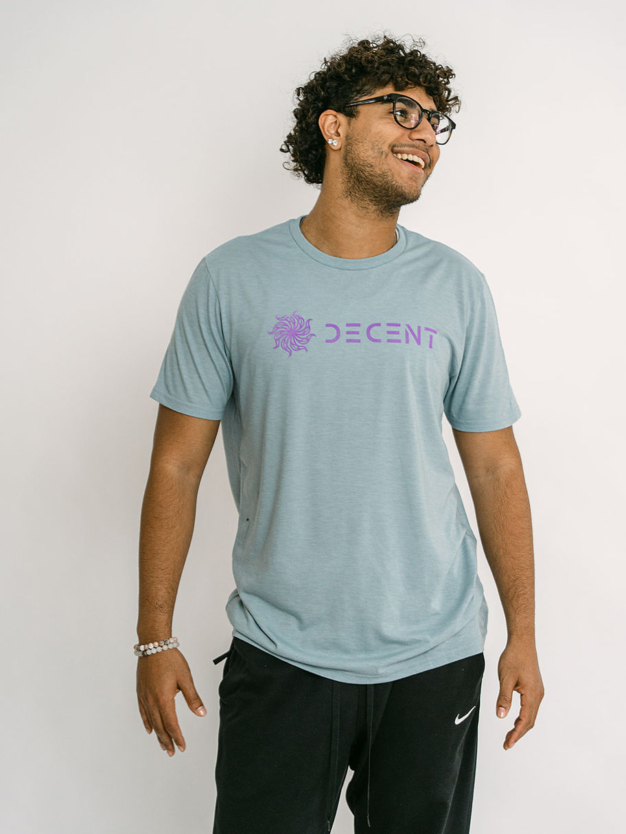 Smiling man with curly hair wearing glasses and a light blue Decent Threads t-shirt