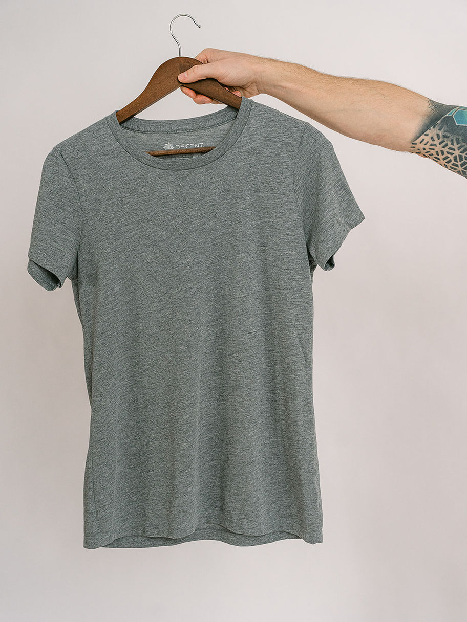 Hand holding grey Decent Threads t-shirt with pink logo design