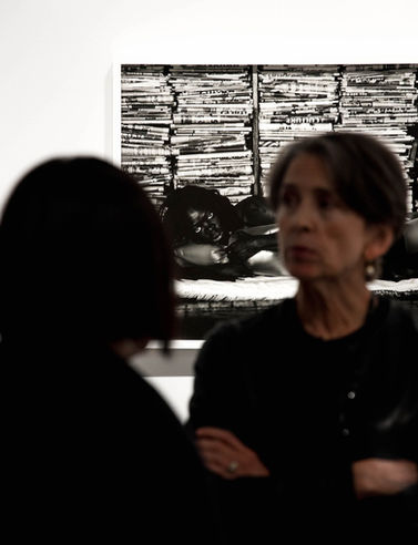 two women are looking at a black and white photo of a woman laying on a bed