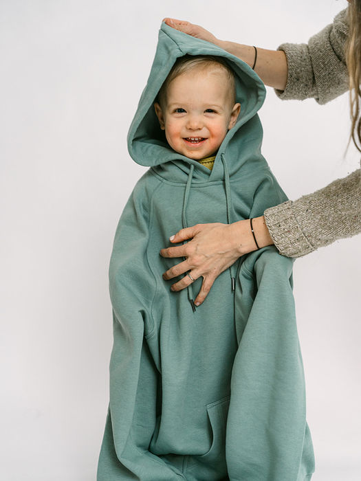 Smiling child wearing an oversized matcha Decent Threads hoodie