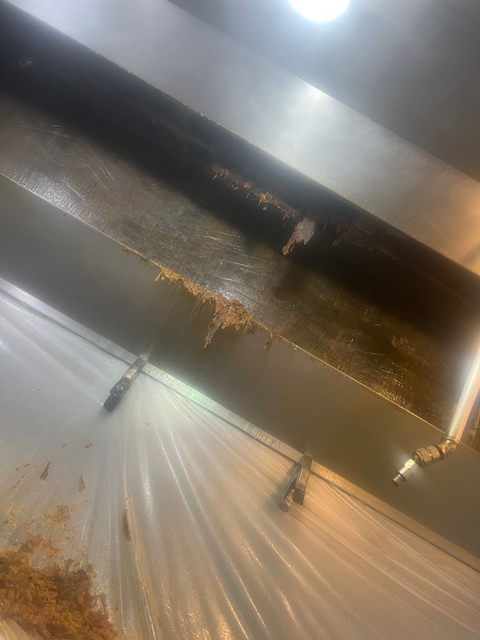 Heavy grease buildup on a filthy commercial kitchen exhaust hood.