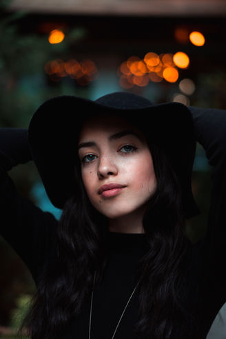 a woman wearing a black hat looks at the camera