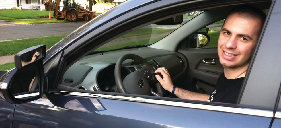 Smiling man sitting in the driver's seat of a car