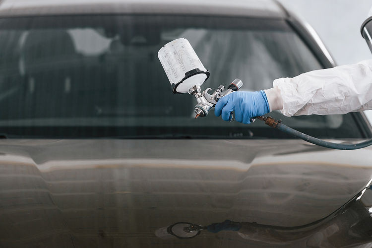 Mobile auto paint specialist restoring a car’s exterior with professional tools.
