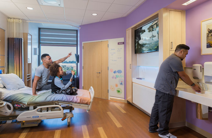 Os quartos hospitalares individuais são espaçosos o suficiente para sofás-camas embutidos que acomodam até dois parentes, um armário dedicado à família, espaço de armazenamento e uma estação de carregamento para laptop - PerkinsWill.