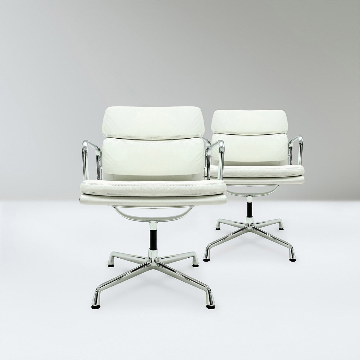 A pair of original Vitra, Eames EA208 Ivory leather and chrome Soft pad chairs with revolving bases.