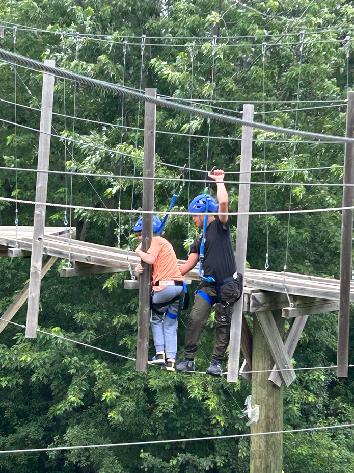 Camper helping another camper on the high ropes course