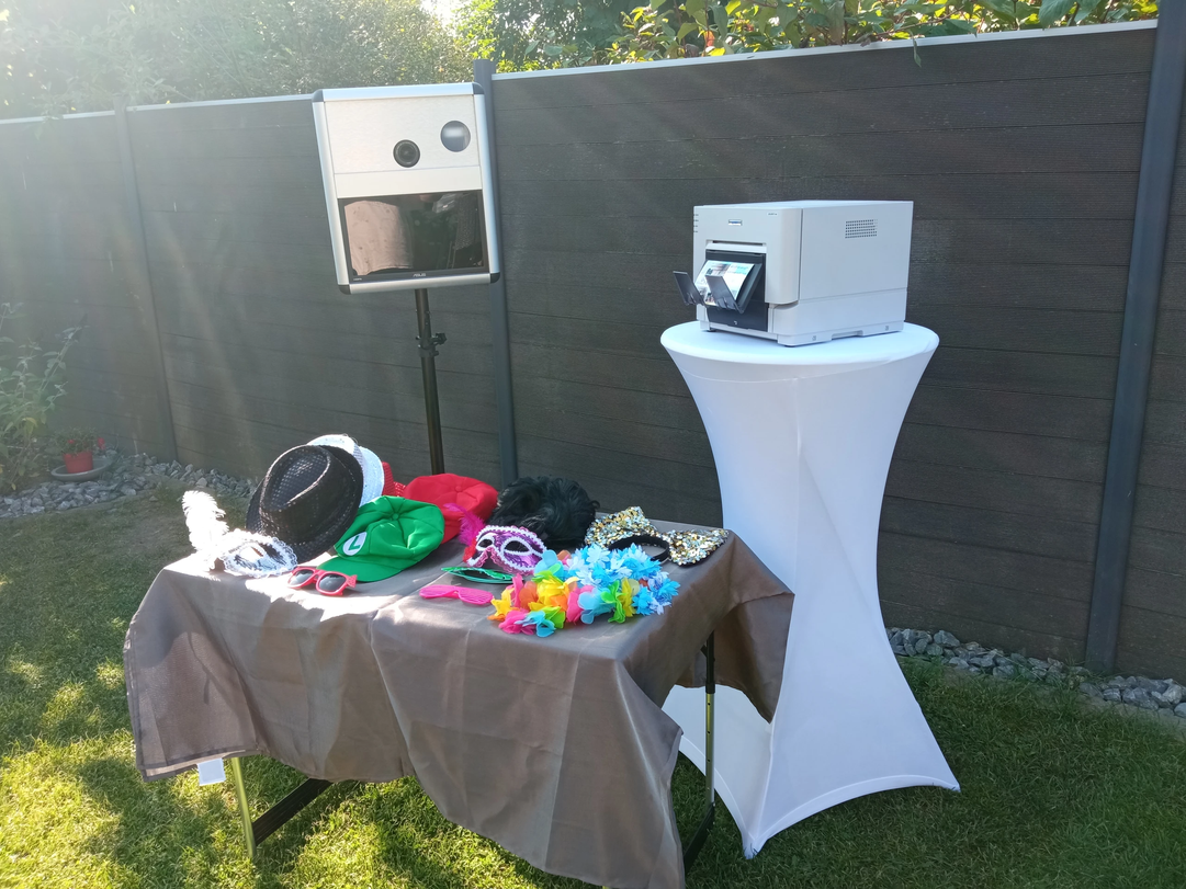 Fotobox mit lustigen Requisiten und Drucker im Garten bereit zur Party.