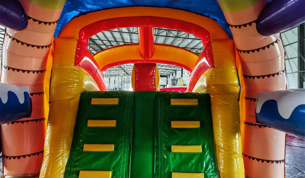 Bunte aufblasbare Spielrutsche mit Kletterstufen in einer Indoor-Anlage.