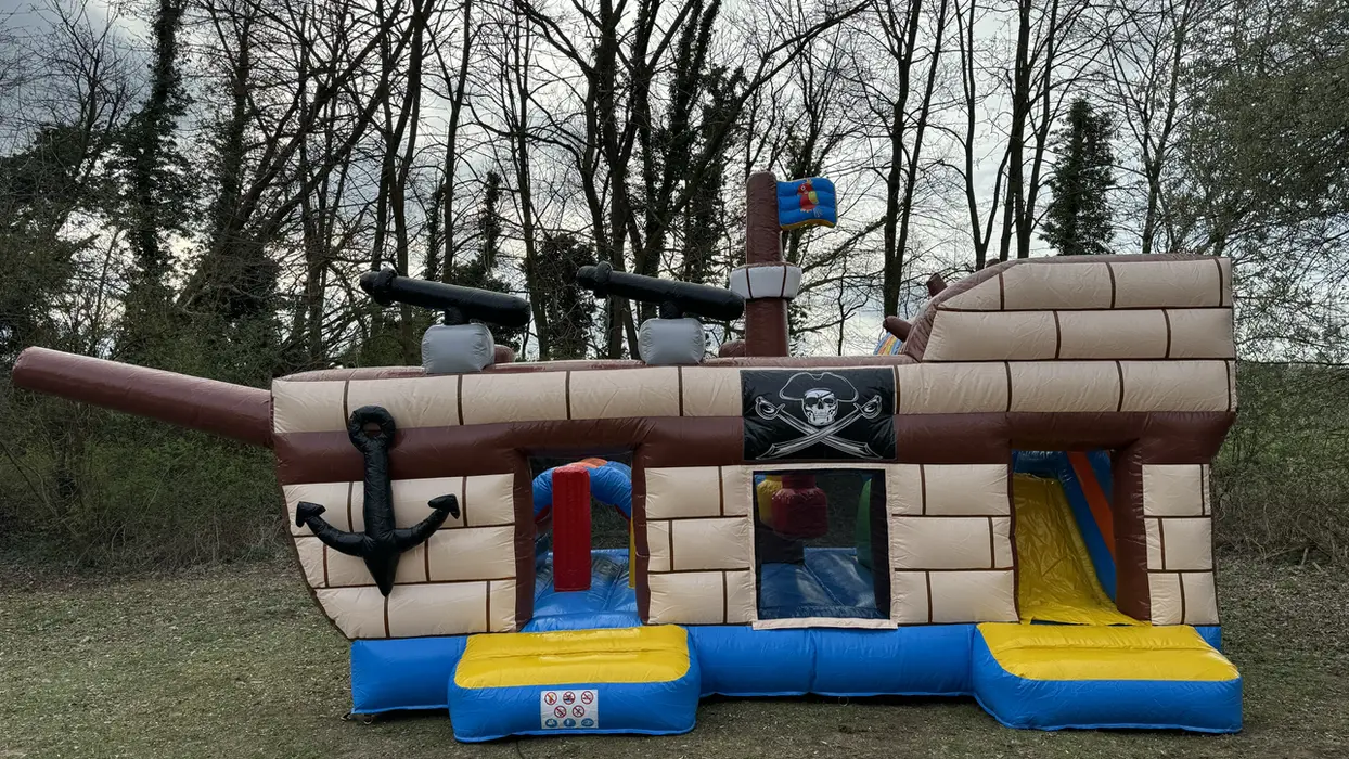 Hüpfburg Piratenschiff mit Kanonen, Anker und Rutsche im Freien.