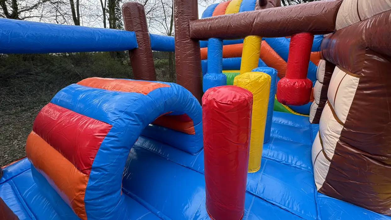 Bunte aufblasbare Hüpfburg mit Tunneln und Hindernissen für Kinder im Freien.
