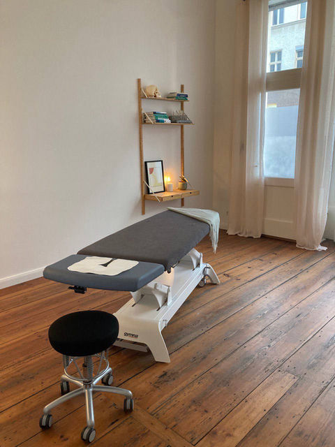 Heller Behandlungsraum für Osteopathie bei DREIRAUM Berlin mit moderner Behandlungsliege und Holzdielenboden.