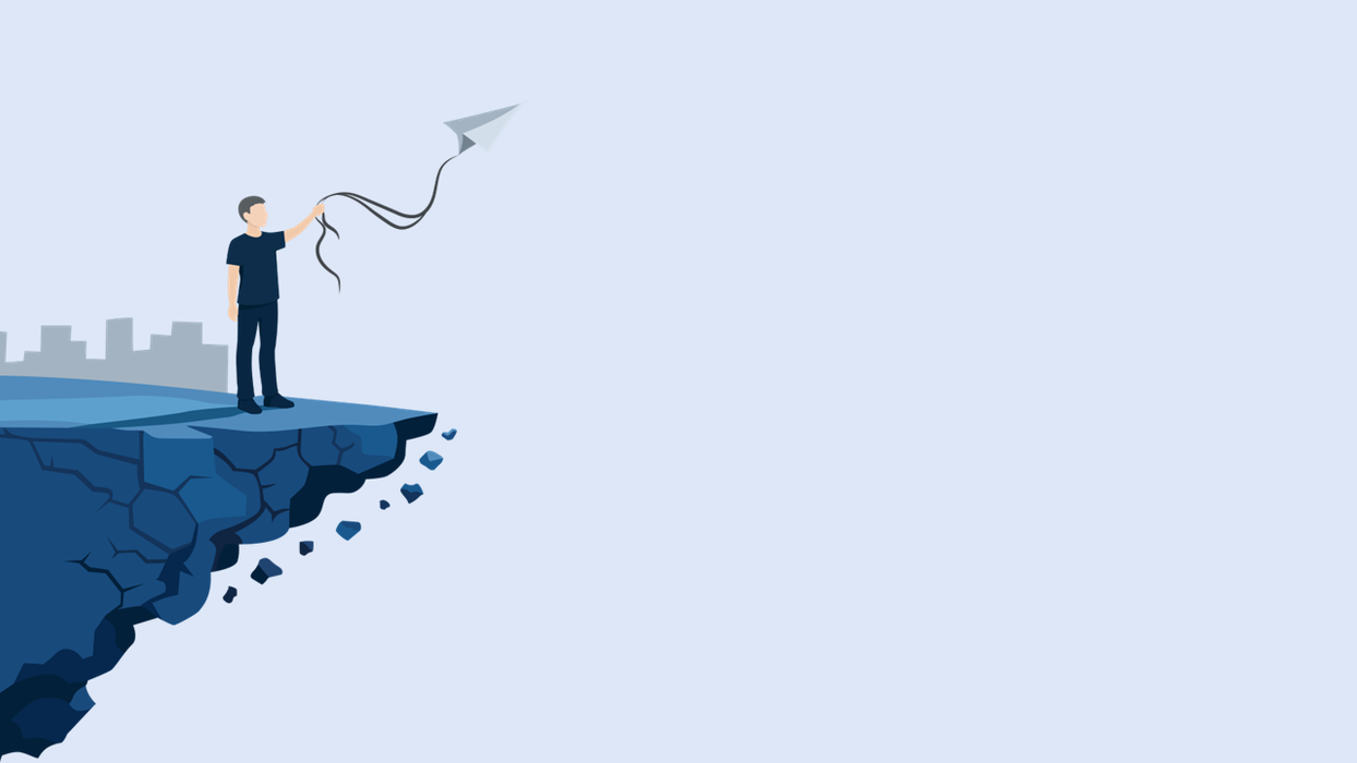 Man flying paper airplane from crumbling cliff edge, city background.