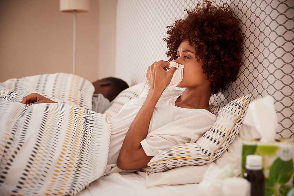 Woman sitting up in bed, looking tired and contemplative, dealing with seasonal allergies.