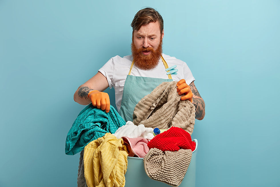 Indignant bearded man holding dirty laundry, preparing for a spring cleaning refresh.