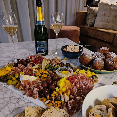 Gevulde borrelplank met oliebollen, cremant en toast in een huiselijke setting