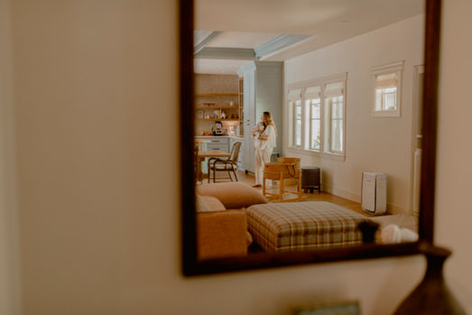 Photo of mirror showing reflection of new mother holding her newborn in her home.