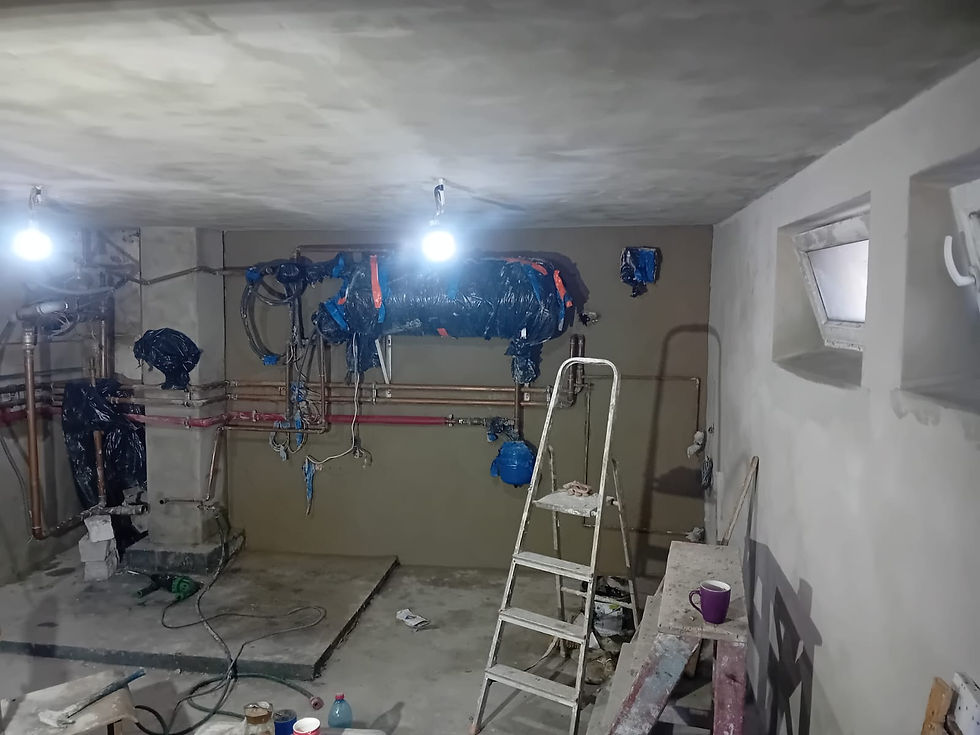 Remontowana kotłownia w Radeczu. Na zdjęciu widać fragment starej instalacji i rury, obok leżą narzędzia i worek ze śmieciami, a w centrum stoi drabina.