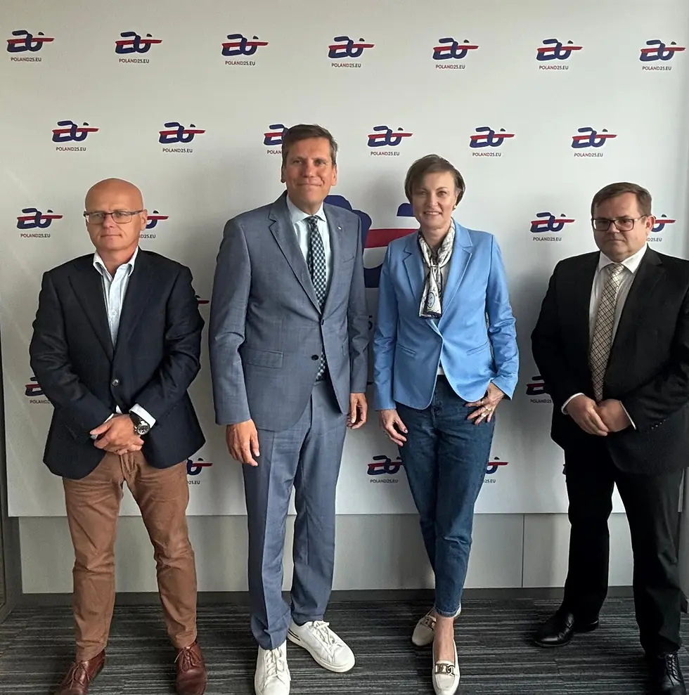 Uczestnicy spotkania w Brukseli, stojący w rzędzie na tle ściany z logotypem polskiego przedstawicielstwa w UE. Od lewej: Łukasz Wojtas, Szef Wydziału Infrastruktury, Arkadiusz Pluciński, Zastępca Stałego Przedstawiciela RP, Agnieszka Wasilewska – Semail, Prezes PKP CARGO S.A., oraz Tomasz Lachowicz, kierujący Przedstawicielstwem PKP w Brukseli.