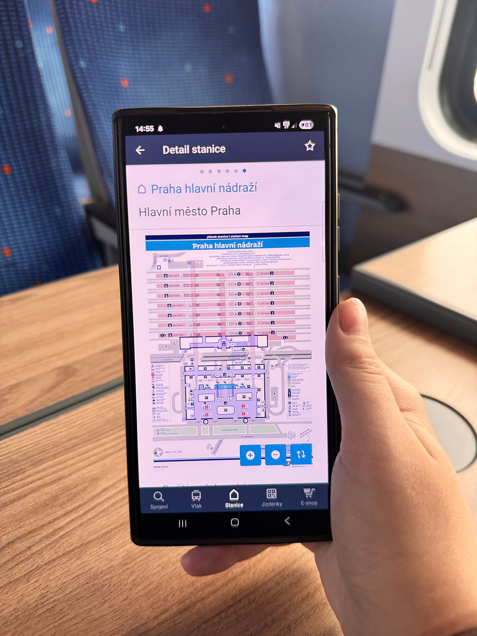 Nowy plan stacji w aplikacji Můj vlak od Českich dráh. Na zdjęciu widać dłoń trzymającą smartfon z wyświetloną aplikacją, prezentującą schemat stacji Praga Główna.
