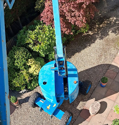 High-angle bird's-eye view looking straight down from a boom lift basket at the machine's base and wheels positioned on a gravel driveway outside the property on Ellislea Road, Broughty Ferry, Dundee