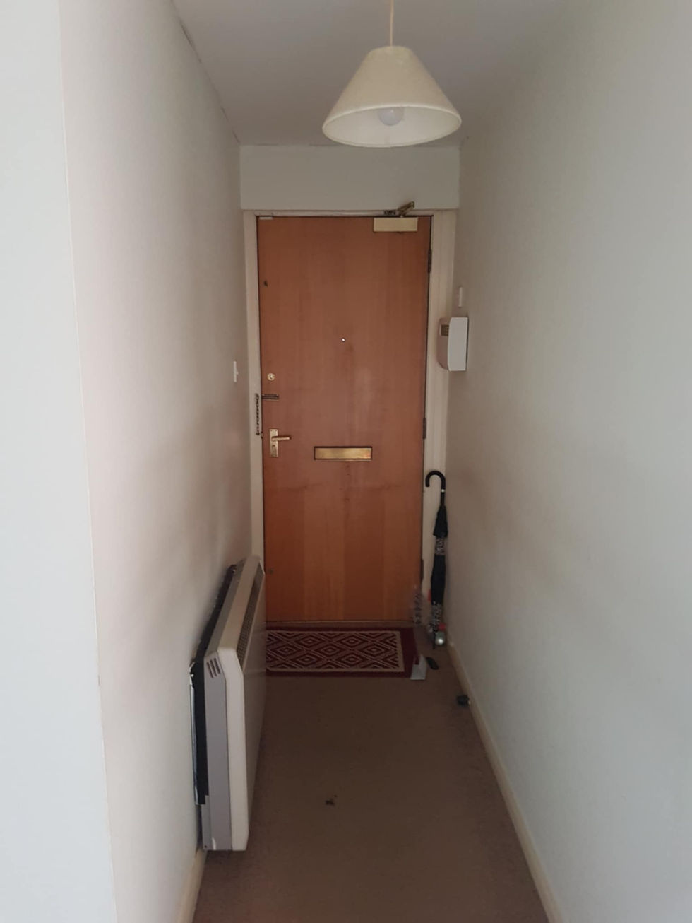 a hallway with a wooden door and an umbrella on the floor