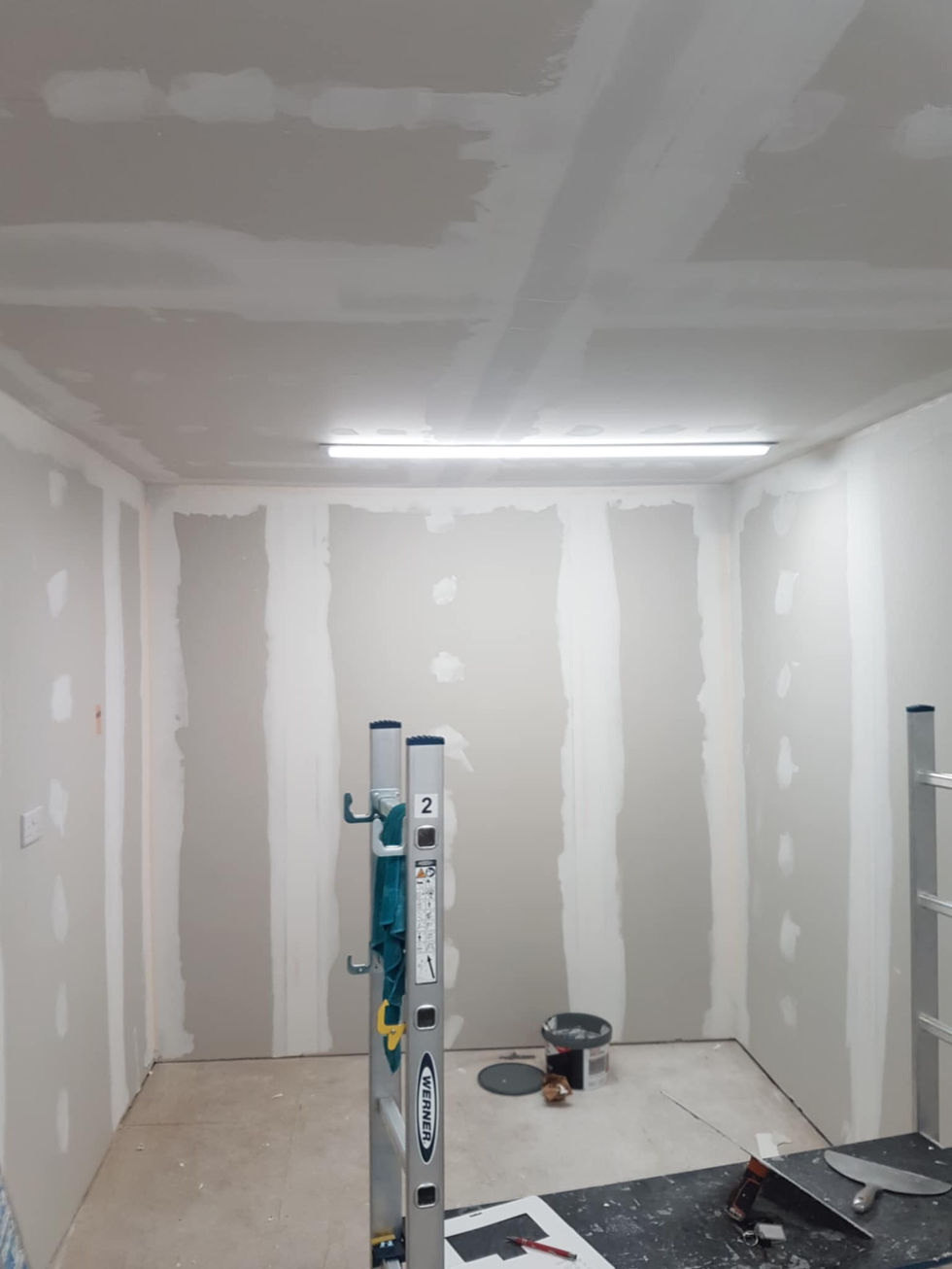 Drywall installation in progress, showing textured walls and ceiling