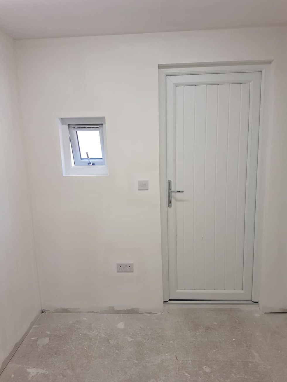 White door and small window in a newly plastered room
