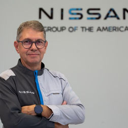 Executivo da Nissan, Marco Biancolini, posa de braços cruzados em frente ao logo da empresa.