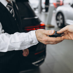 Cliente recebe chave de carro em concessionária durante processo de compra financiada.