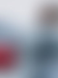 Carro elétrico sendo recarregado em ponto de carregamento, com uma mulher ao lado usando o celular.