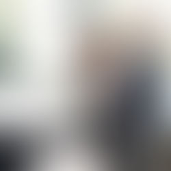 Consultor de concessionária conversa com casal ao lado de um carro branco, em ambiente de showroom, durante negociação de compra de veículo.