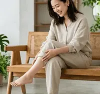 清潔感のある室内で、軽くなった自分の足を触りながら微笑む20代の女性