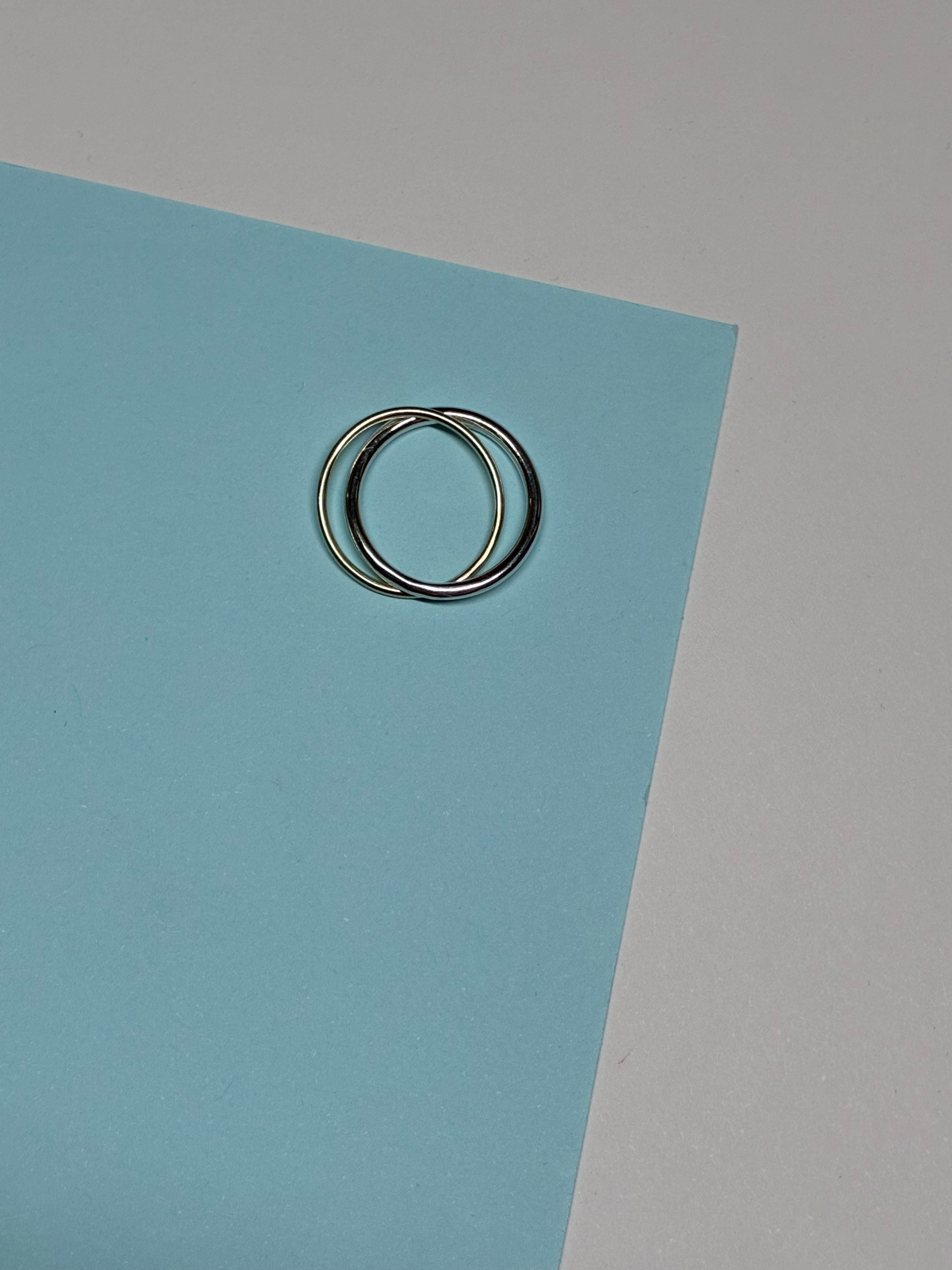 Twee in elkaar verstrengelde ringen op blauw papier