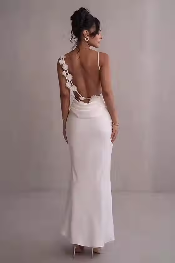 Back view of an ivory fitted gown with a low draped back and floral details along the straps for a rehearsal dinner.