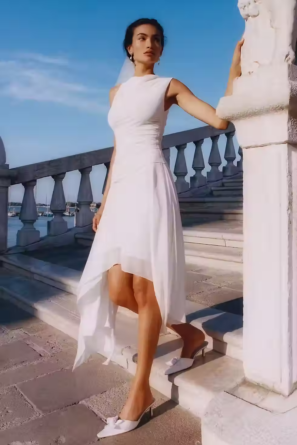 White midi dress with an asymmetrical neckline and draped silhouette for an elevated engagement party outfit.