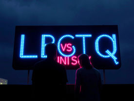 Silhouetted man and woman at a neon billboard reading LGBTQ vs UNISEX, glowing blue and pink against a dark night sky. | Beyond the Guard: Unisex, Hybridity, and the Social Landscape Path to Regulation