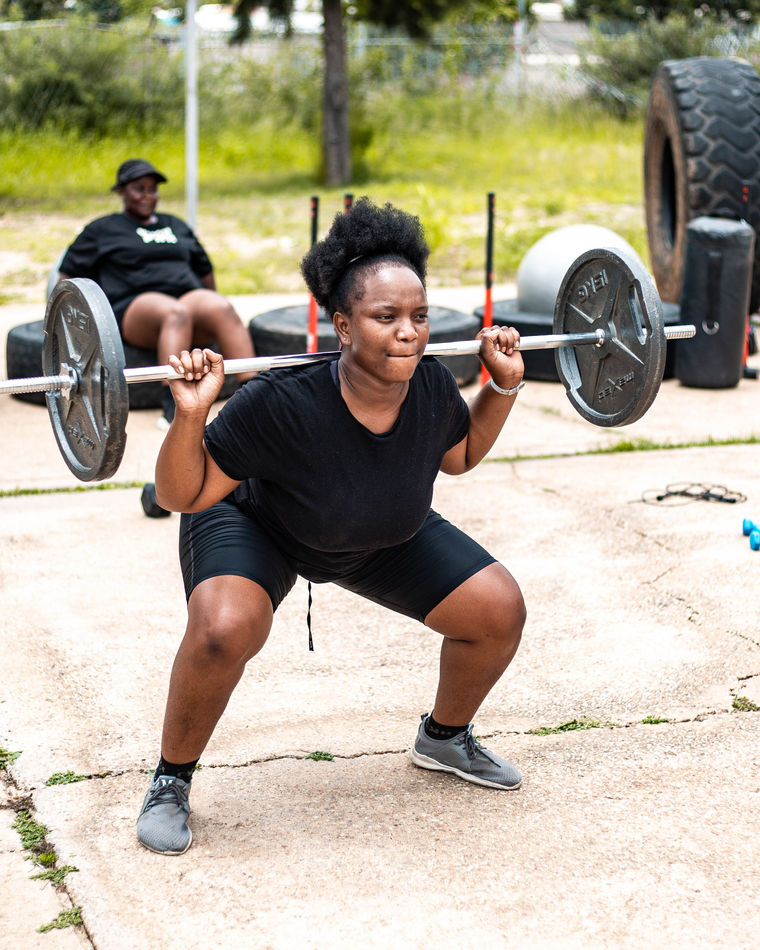A member performing a barbell squat at an outdoor session
