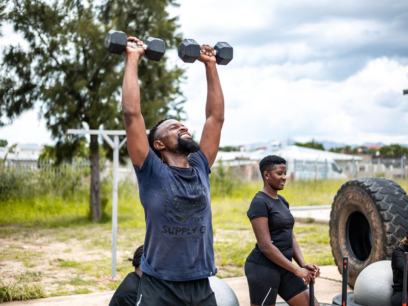 A member pressing dumbbells overhead during a session