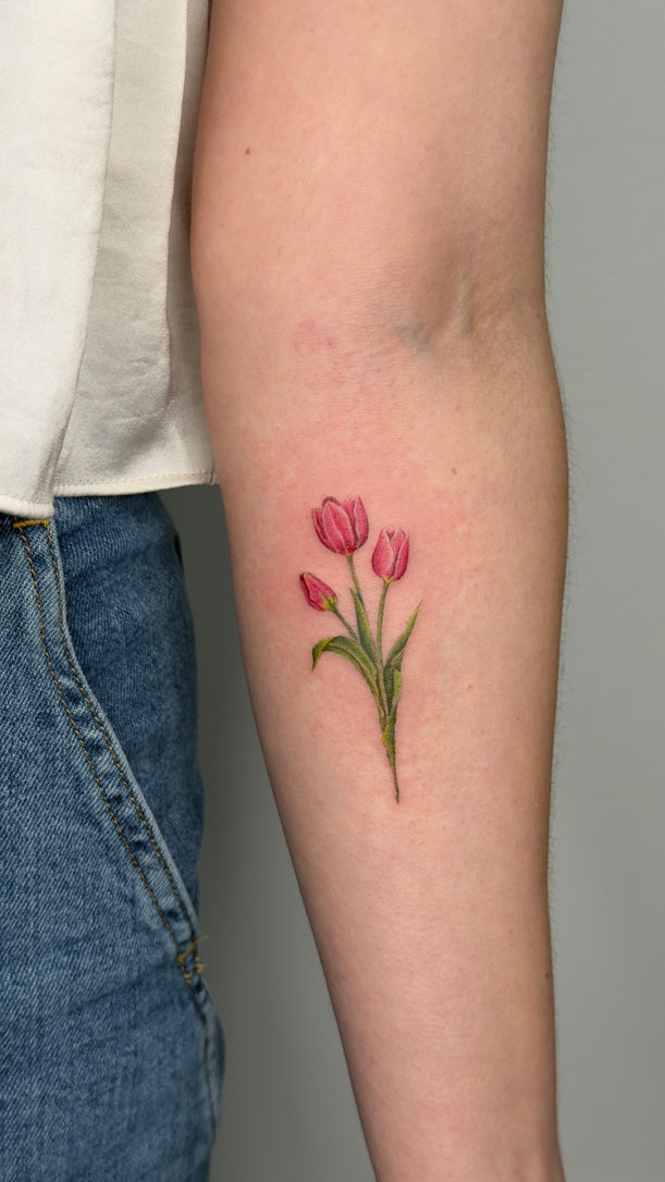 Small red tulip color tattoo on the forearm