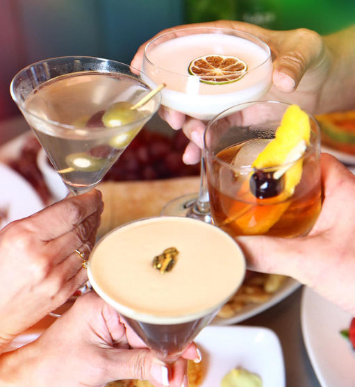 A group of friends sharing a toast with a Dirty Martini, Old Fashioned, Espresso Martini and a Wild Olives 30A craft cocktail You, Me & The Sea.